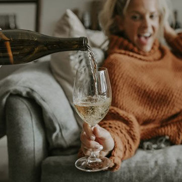 Woman Drinking a Glass of Wine with Popcorn in a Bowl in Front of Her